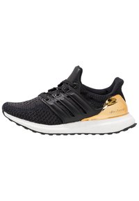 Černá sportovní bota s pleteným svrškem, třemi lesklými černými pruhy, zlatým akcentem na patě a bílou polstrovanou mezipodešví.