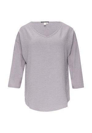 Blouse longue à manches longues de couleur violet clair avec décolleté en V et tissu texturé à l'avant, étiquetée taille petit, présentée sur fond blanc.