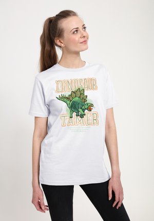Hvid bomulds t-shirt med et grafisk motiv af en dinosaur og teksten "Dinosaur Tamer" i orange og grøn. Korte ærmer, afslappet pasform.
