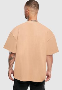 Beež oversized t-särk lühikeste varrukatega, ribatud ümar kaelus ja sile tekstuur. Omab lihtsat disaini, ilma nähtavate mustrite või aktsentideta.