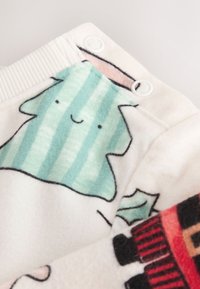 Fleece fabric with a cream background, featuring a green striped tree and colorful accents. Includes snap closures and ribbed elastic at the top.