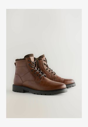 Bruine leren enkellaarsjes met een gladde textuur, voorzien van een vetersluiting aan de voorkant, een zijrits en een robuuste rubberen zool voor grip.