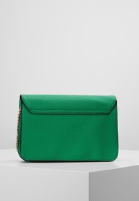 Grön läderkuvertväska med en strukturerad yta, svarta kanter och en kedjesnor. Har ett klaffstängning och en rektangulär form.