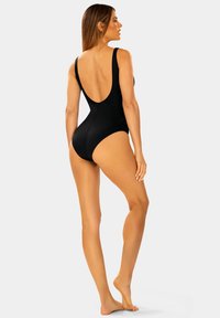 Czarny jednoczęściowy strój kąpielowy z niskim plecami, szerokimi ramiączkami i gładką teksturą. Zaprojektowany, aby uzyskać czystą sylwetkę z minimalnymi akcentami.