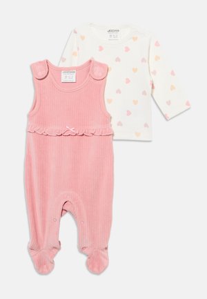 Body bébé rose sans manches en maille côtelée avec détail volanté, associé à une chemise blanche à manches longues avec petits imprimés de cœurs pastels.