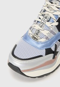 Mesh sneaker with a bluish-silver upper, black accents, and textured overlays. Features white laces and a thick rubber sole.
