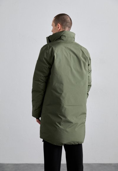 Long puffer coat in olive green, featuring a high collar and a smooth, textured finish. The coat extends past the hips and has long sleeves.