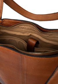 Bolso de cuero marrón con cierre de cremallera. El interior está forrado con tela beige y cuenta con bolsillos organizadores y una correa.
