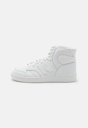 Hoher weißer Sneaker mit Schnürsenkeln, genähten Einsätzen und einer strukturierten Sohle, von der Seite auf einem schlichten hellen Hintergrund gezeigt.