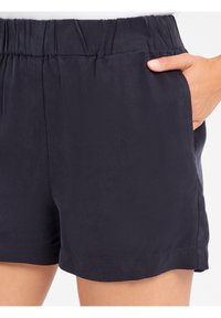 Marineblauwe shorts van een textuurstof, met een elastische tailleband en zijzakken. Heeft een losse pasvorm en een relaxte zoom.