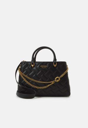 Schwarze gesteppte Lederhandtasche mit zwei kurzen Griffen, goldener Kettenriemen und goldenem "GUESS EST 1981"-Logo vorne.
