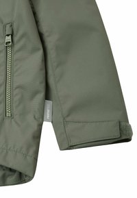 Manica di giacca verde isolata con tasca con zip, chiusura in Velcro e etichetta con il marchio "remotETC". Tessuto liscio e resistente.