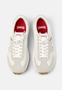 Bílé a světle šedé tenisky s semišovými a koženými panely, bílé šnůrky, červená stélka a hnědý akcent po straně.