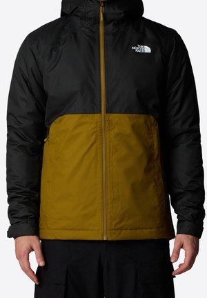 Sort og sennepsfarvet todelt hættejakke med frontlynlås og The North Face-logo på venstre bryst, båret af en person med synlige hænder.