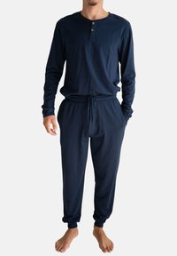 Marineblauw pyjamaset met lange mouwen van zachte stof. Voorzien van een knoopsluiting bij de hals en een elastische tailleband met trekkoord. Aansluitende manchetten.