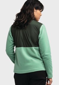 Mintgrüner Pullover mit einem dunkelgrünen Einsatz auf der oberen Rückseite. Hergestellt aus weichem Stoff mit einer lockeren Passform und langen Ärmeln.