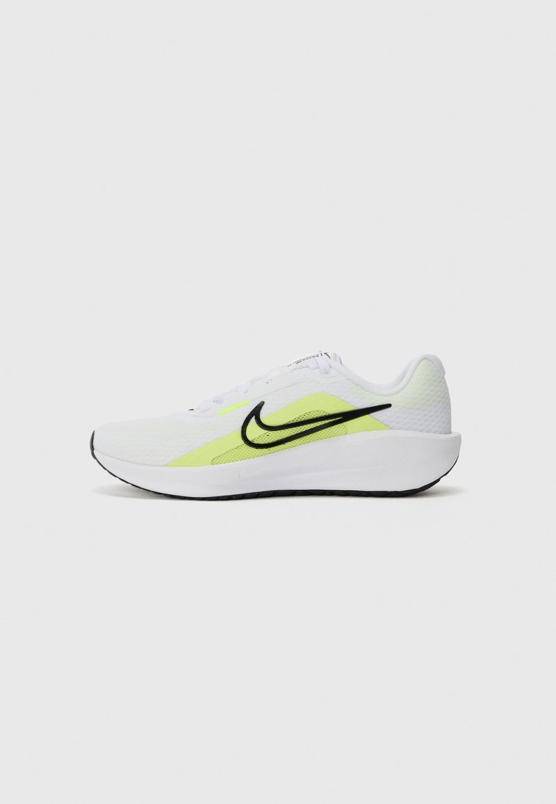 Nike løbesko har en hvid mesh-overdel med en sort swoosh og en neongul accent. SÅlen er tyk og struktureret for støtte.