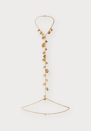 Goudkleurige sieraden met een delicate ketting en bladeren als accenten, die een watervalontwerp creëren. Gladde oppervlakken met gestructureerde details.