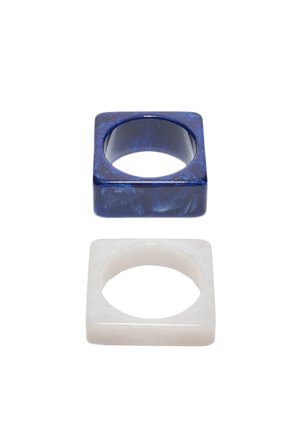 Two square-shaped resin rings, one dark blue with marbled texture and one translucent white, on a white background.
