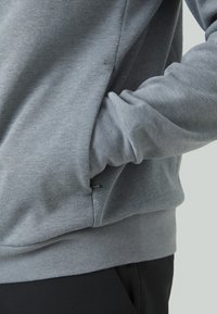 Gray sweatshirt made of soft fabric with ribbed cuffs and hem, featuring a side pocket and minimalistic design with a small logo detail.