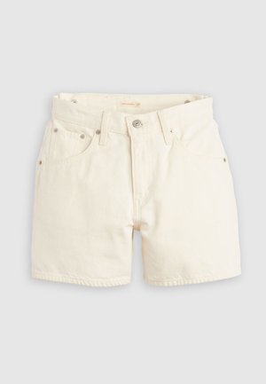 Valged teksapüksid, millel on kõrge vöökoht, neli taskut ja metallist riistvara. Kangas on sileda tekstuuriga ja nähtavate õmblustega.