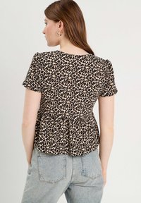Haut peplum en imprimé léopard beige et noir avec des manches courtes, en tissu doux, encolure arrondie et détail froncé à la taille.