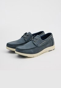 Zapatos de barco de piel azul para hombres con puntera redondeada, suela de goma blanca y ojales metálicos para los cordones. Textura suave con detalles de costura.