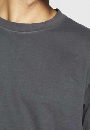 Close-up of a person's upper chest and neck wearing a plain dark gray crew neck t-shirt.