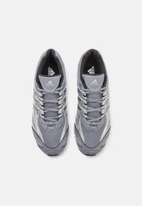 Par tenisica za trčanje u sivoj boji marke Adidas s mrežastim gornjim dijelom, vezicama i crnim ulo�žkom za udobnost, gornji pogled na bijeloj pozadini.