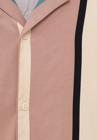 Camicia a maniche corte di un rosa chiaro con strisce verticali crema e nere. Presenta un colletto a punta e chiusura con bottoni, tessuto strutturato.