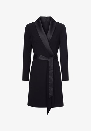 Zwarte wikkeljurk met lange mouwen, satijnen revers en riem. De stof lijkt glad met een gestructureerde vorm en een ritsluiting aan de achterkant.