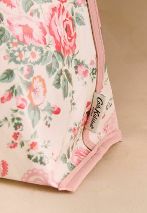 Roh látkové tašky s květinovým vzorem, růžovým lemováním a viditelnou etiketou Cath Kidston London na béžovém povrchu.