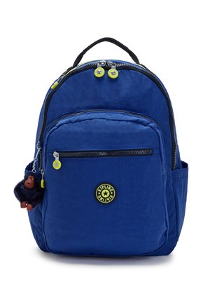 Zaino blu realizzato in tessuto resistente, dotato di una tasca frontale con zip, rifiniture nere e un portachiavi a forma di scimmia. Design arrotondato con doppie cerniere.