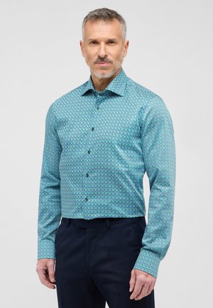 Groene blouse met een patroon en een button-down kraag, met een geometrisch ontwerp in blauw en zwart, lange mouwen en een getailleerde pasvorm.