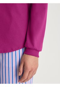 Fuchsia langarmshirt met geribde manchetten, gecombineerd met multi-kleurige gestreepte pyjamabroek. Glad materiaal met een comfortabele pasvorm.