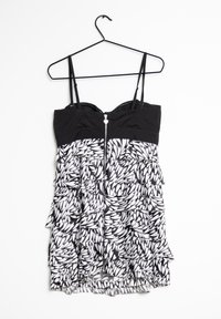 Abito senza spalline bianco e nero con un design a volant, dotato di zip frontale e motivo a foglie. Texture liscia; tessuto leggero.