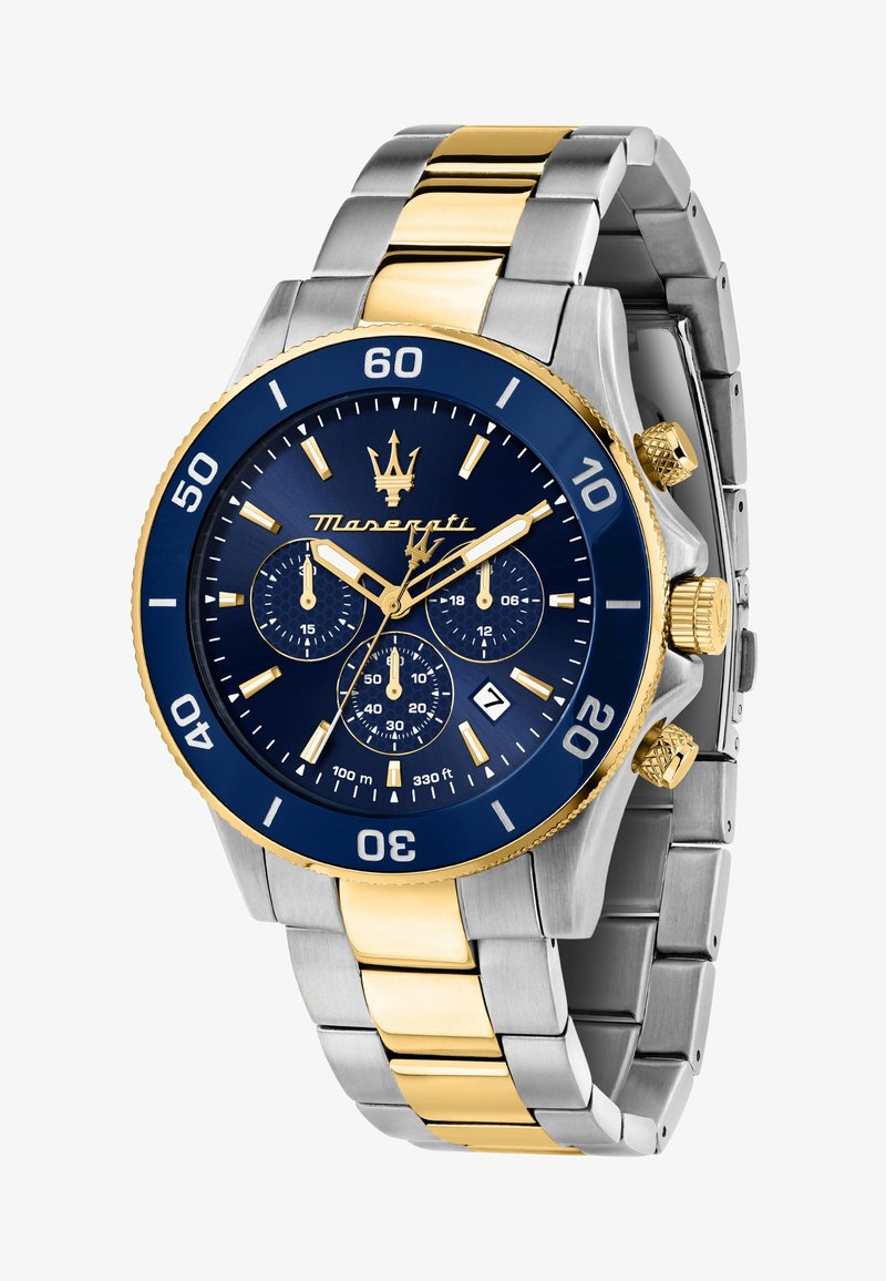 Montre en métal argenté et doré avec un cadran bleu, affichage de la date, trois sous-cadrans et une lunette unidirectionnelle marquée de chiffres.