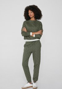 Conjunto de loungewear verde oliva con lunares blancos, que incluye un sudadera corta y pantalones ajustados a juego, confeccionado en un tejido suave.