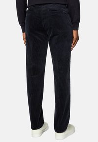 Navy corduroy pants with a textured finish, straight fit, and two back pockets, worn with white sneakers on a light background.