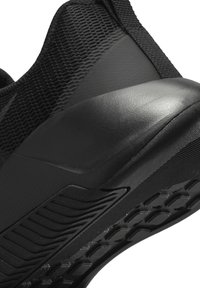 Schwarzer Sportschuh mit einer strukturierten Mesh-Oberfläche, Gummisohle mit Traktionsmuster und geformten Akzenten zur Unterstützung.