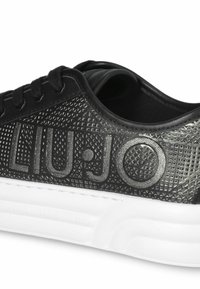 Sneaker nera con tomaia testurizzata caratterizzata da motivi geometrici in rilievo, logo "LIU.JO", lacci neri e suola in gomma bianca.