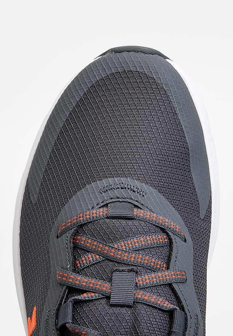 Grauer Sportschuh mit strukturiertem Mesh-Obermaterial, orangefarbenen Akzentnähten und einer weißen Sohle. Verfügt über verstärkte Ösen und flache Schnürsenkel.