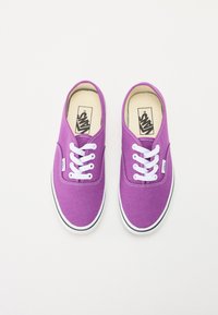 Purple canvas sneakers with white laces, round toe, and black trim on the sole. Featuring a Vans logo on the tongue.