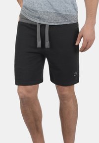 Pantalones cortos de sudor negro hechos de una suave mezcla de algodón, con una cintura elástica ajustable en gris y un logotipo sencillo en el lado inferior.