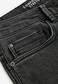 Černé džínové kalhoty, které ukazují detailní pohled na kapsu s vyšívanými detaily a stříbrným knoflíkem, se soft touch texturou.
