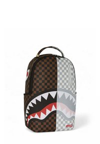 Zaino con un motivo a scacchi in marrone e grigio, caratterizzato da un ampio design di squalo con dettagli rossi e denti bianchi. Chiusura con zip e maniglia.