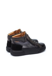 Zapatillas altas de cuero negro con un acabado suave, cremalleras laterales y acentos de ante negro texturizado. Suela de goma con diseño estriado.
