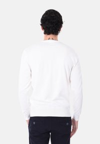 Maglione bianco realizzato in un morbido materiale a maglia. Presenta maniche lunghe, polsini in costina e vita aderente. Design posteriore semplice.