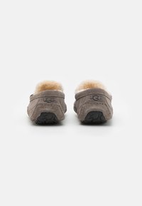 Barna nubuk papucsok puha, bolyhos béléssel és texturált gumi talppal. Az UGG logo látható a hátsó részen.