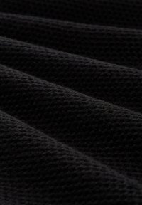 Schwarzer Textilstoff mit einem gewebten Muster, das ausgeprägte Rillen und eine weiche, leicht erhabene Oberfläche aufweist.